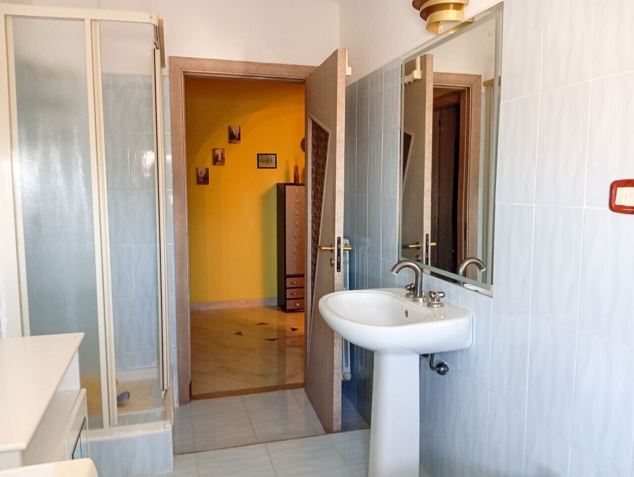 A bathroom with a white sink, a mirror, and a shower area.