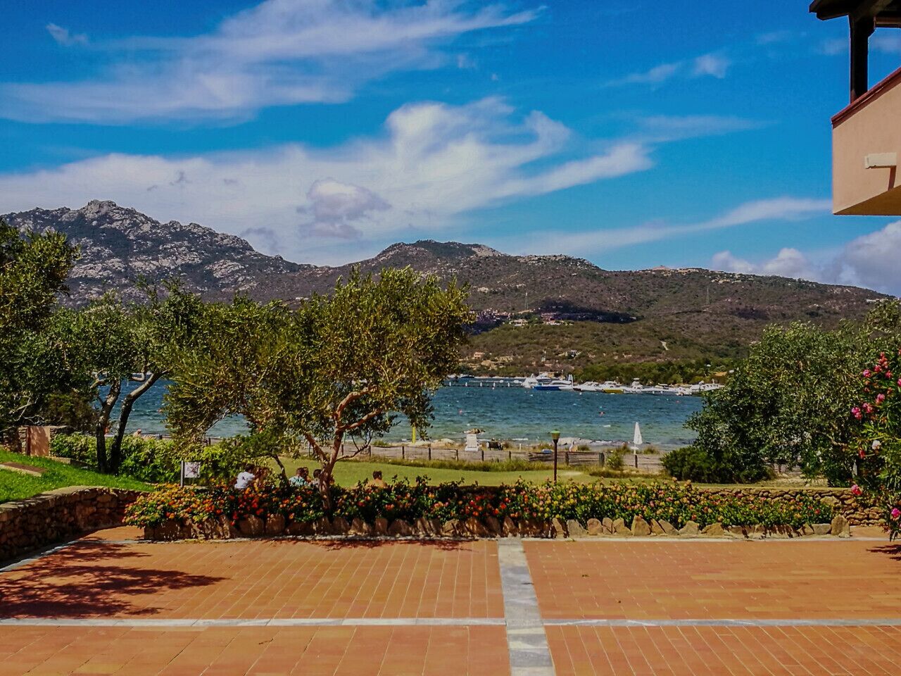 Eine gepflasterte Terrasse mit Blick auf ein Gewässer und Berge.