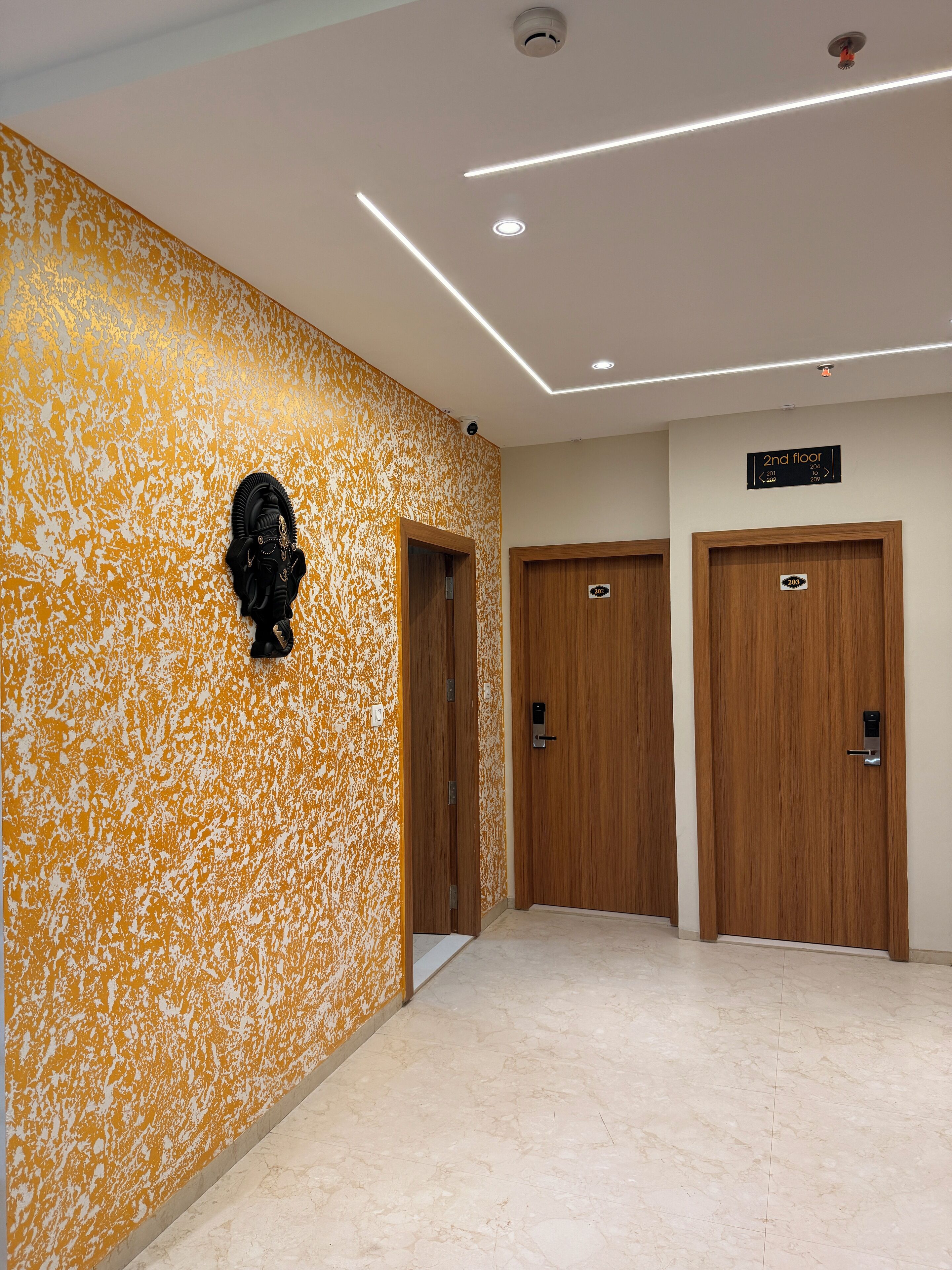 Ein Flur mit strukturierter Wand, zwei Holztüren und einem Schild, das die 2. Etage anzeigt.