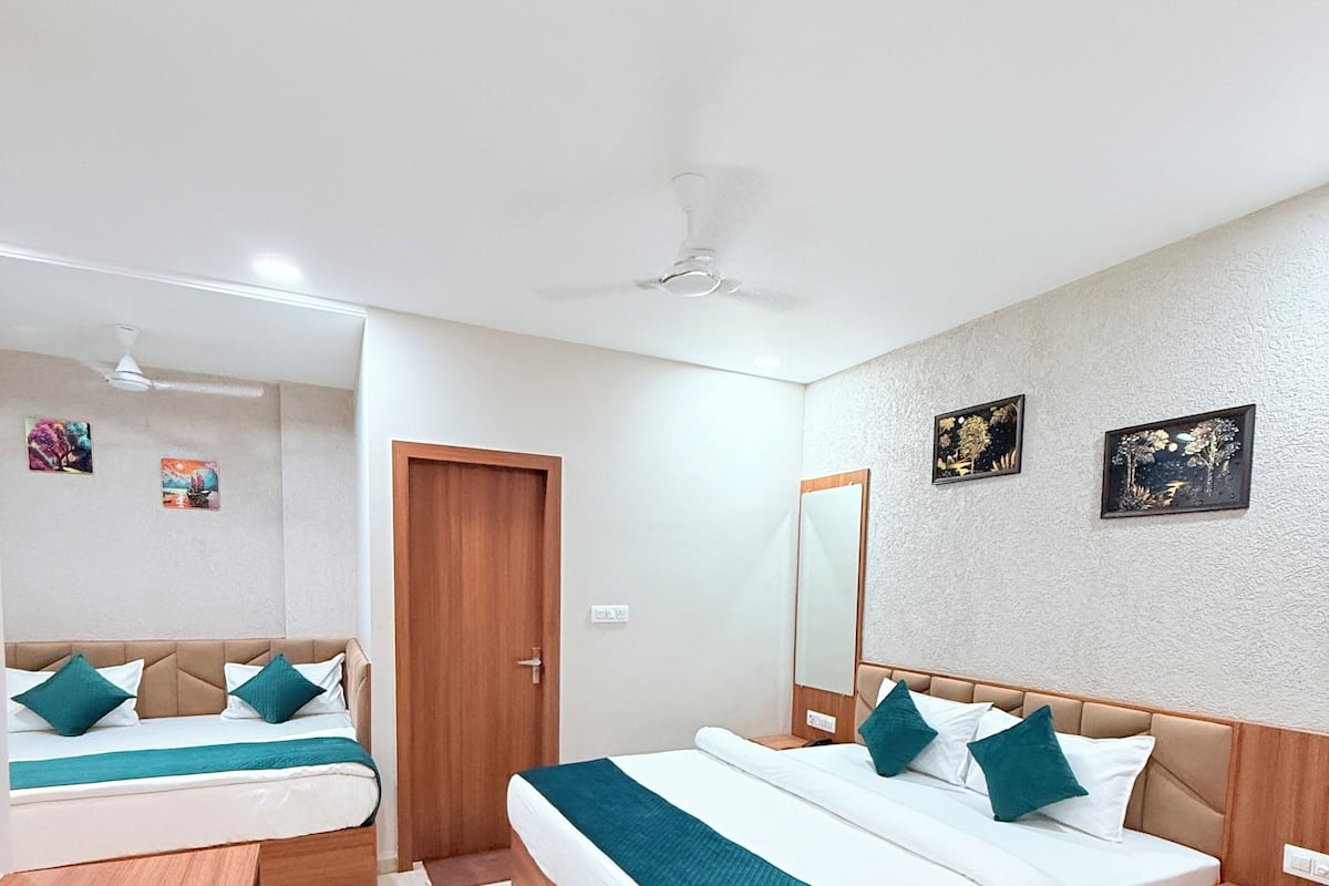 A hotel room with two beds, a wooden desk, a mirror, and a ceiling fan.
