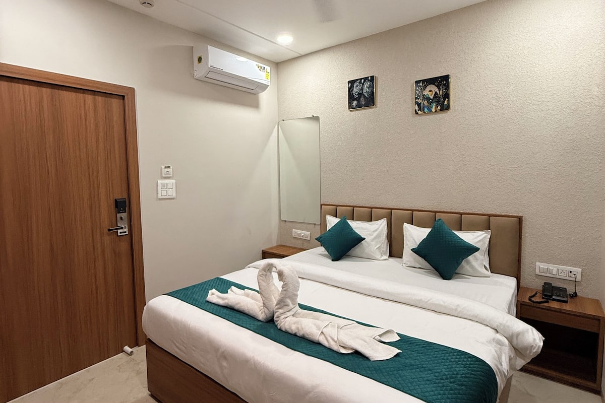 A hotel room with two beds, a ceiling fan, an air conditioning unit, and a small bedside table with a phone.