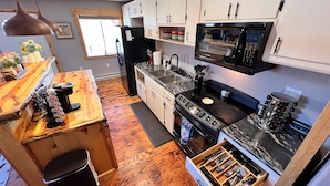 Cocina compacta con armarios de madera, un microondas integrado, estufa y lavamanos.