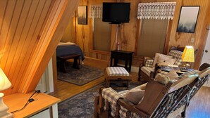 Una habitación acogedora con una cama, un sofá, un banco de madera y un televisor.