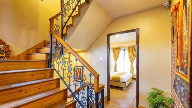 A wooden staircase with a metal railing leading to a bedroom with a bed and curtains. - Bhrikuti Stay (Lalitpur)
