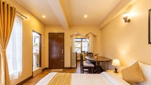 A hotel room with a bed, a dining table, and a chair. - Bhrikuti Stay (Lalitpur)
