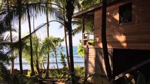 Un edificio de madera con balcón que da a una playa y al océano.