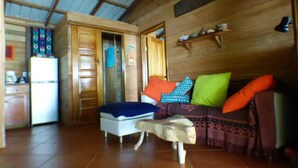 Acogedor interior de cabaña con un comedor de madera, un sofá con cojines de colores y una pequeña mesa.