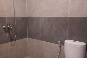 Un baño con ducha, inodoro y grifo de pared.