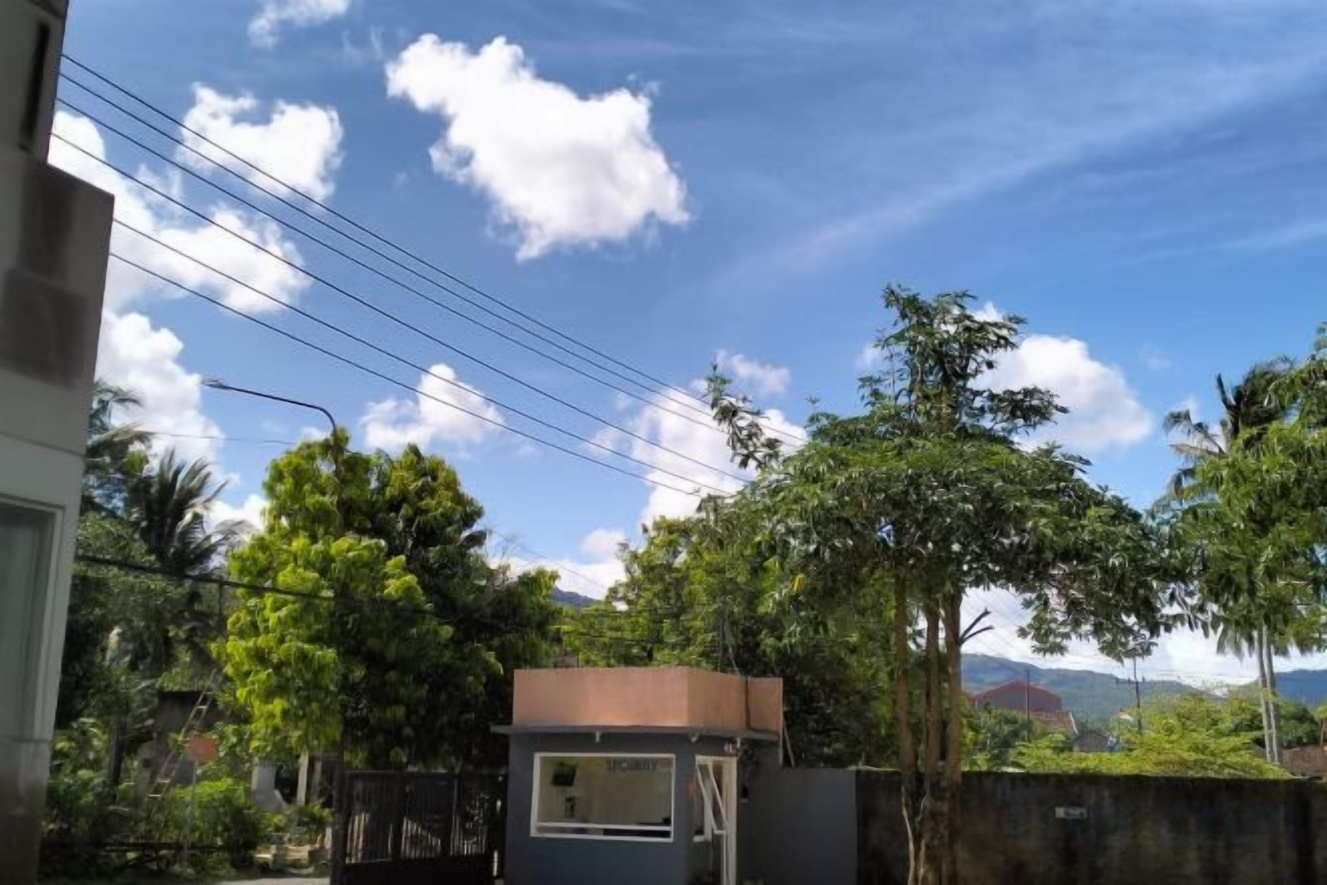 A residential area with a small structure, possibly a shed or a garage, surrounded by trees and a clear sky.