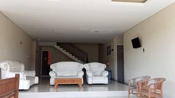 A spacious living area with a staircase leading to another level, a sofa set, and a small table.