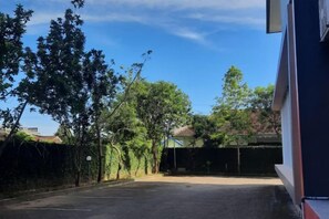 A parking lot with trees and a building in the background. - Hotel Grand Bromo Pacitan (Pacitan)