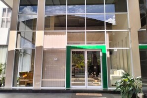 A hotel entrance with a glass facade, a green frame around the door, and a visible staircase leading to the entrance. - Hotel Grand Bromo Pacitan (Pacitan)