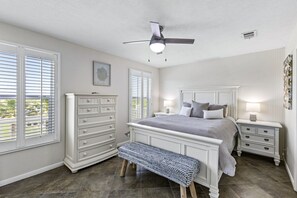 A bedroom with a bed, nightstands, a dresser, a bench, and a ceiling fan. - Near Marina~Near Beach~Chef Kitchen~Games~Balcony (Bolivar Peninsula)