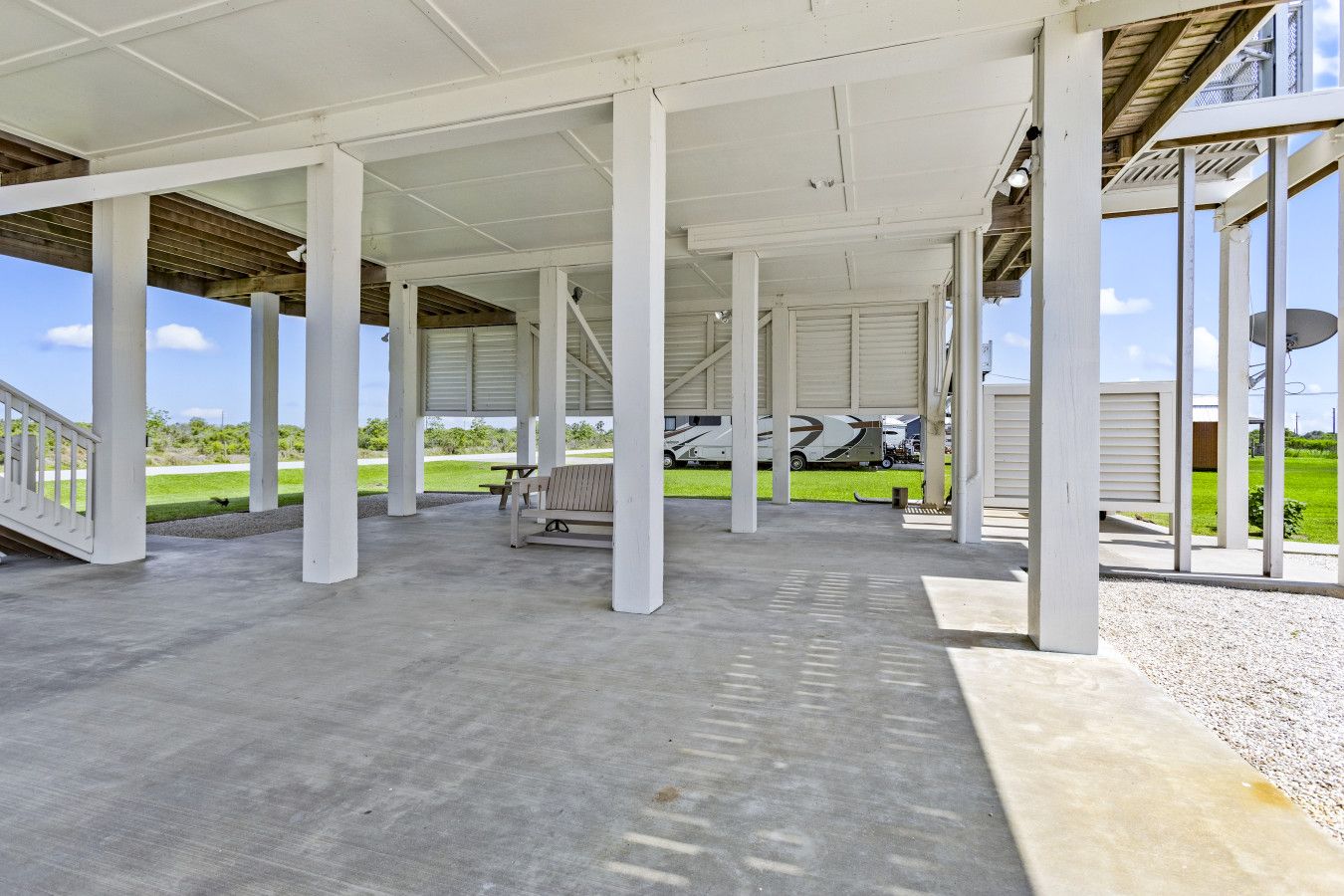 An open pavilion with a concrete floor, white columns, and a bench.