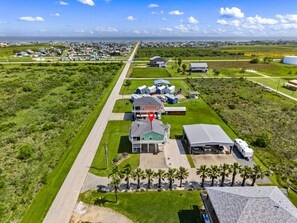 An aerial view of a residential area with a large house, a covered parking area, and a trailer. - Near Marina~Near Beach~Chef Kitchen~Games~Balcony (Bolivar Peninsula)