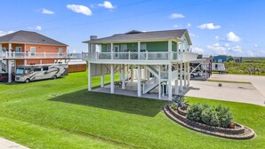 A two-story house with a covered deck and a large RV parked in the driveway. - Near Marina~Near Beach~Chef Kitchen~Games~Balcony (Bolivar Peninsula)