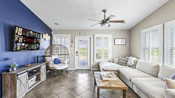 A living room with a blue accent wall, a ceiling fan, a white sofa, a wooden coffee table, and a decorative chair.