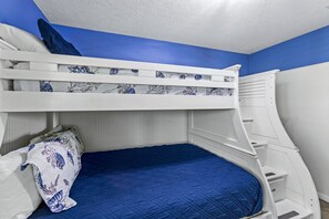 Una cama litera con colchón azul y cabecera blanca.