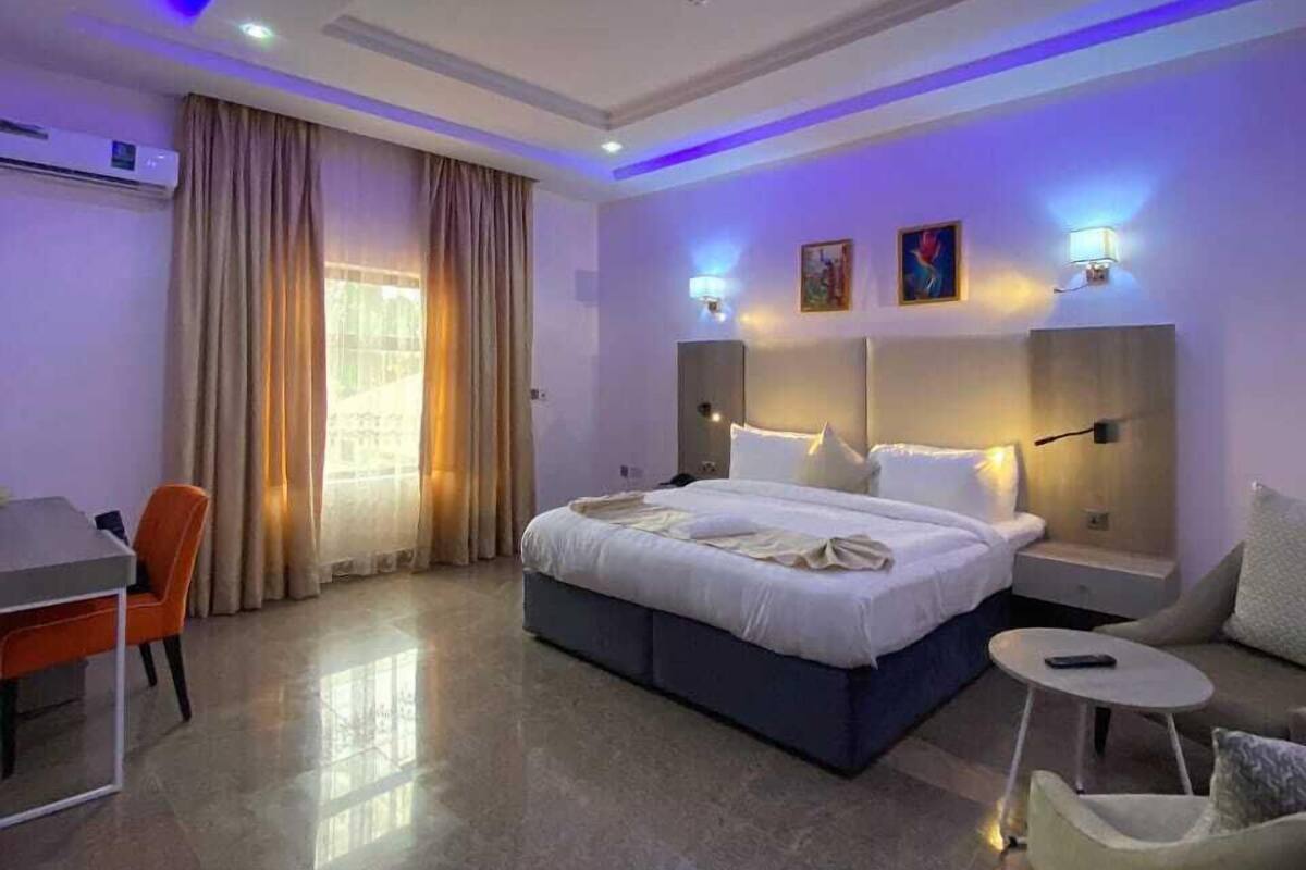 Een moderne hotelkamer met een groot bed, nachtkastjes, een bureau en een stoel.