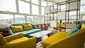A modern lounge area with a green sofa, yellow armchairs, and a white coffee table. - Marchforte-Courtyard Hotel  (Ibadan)