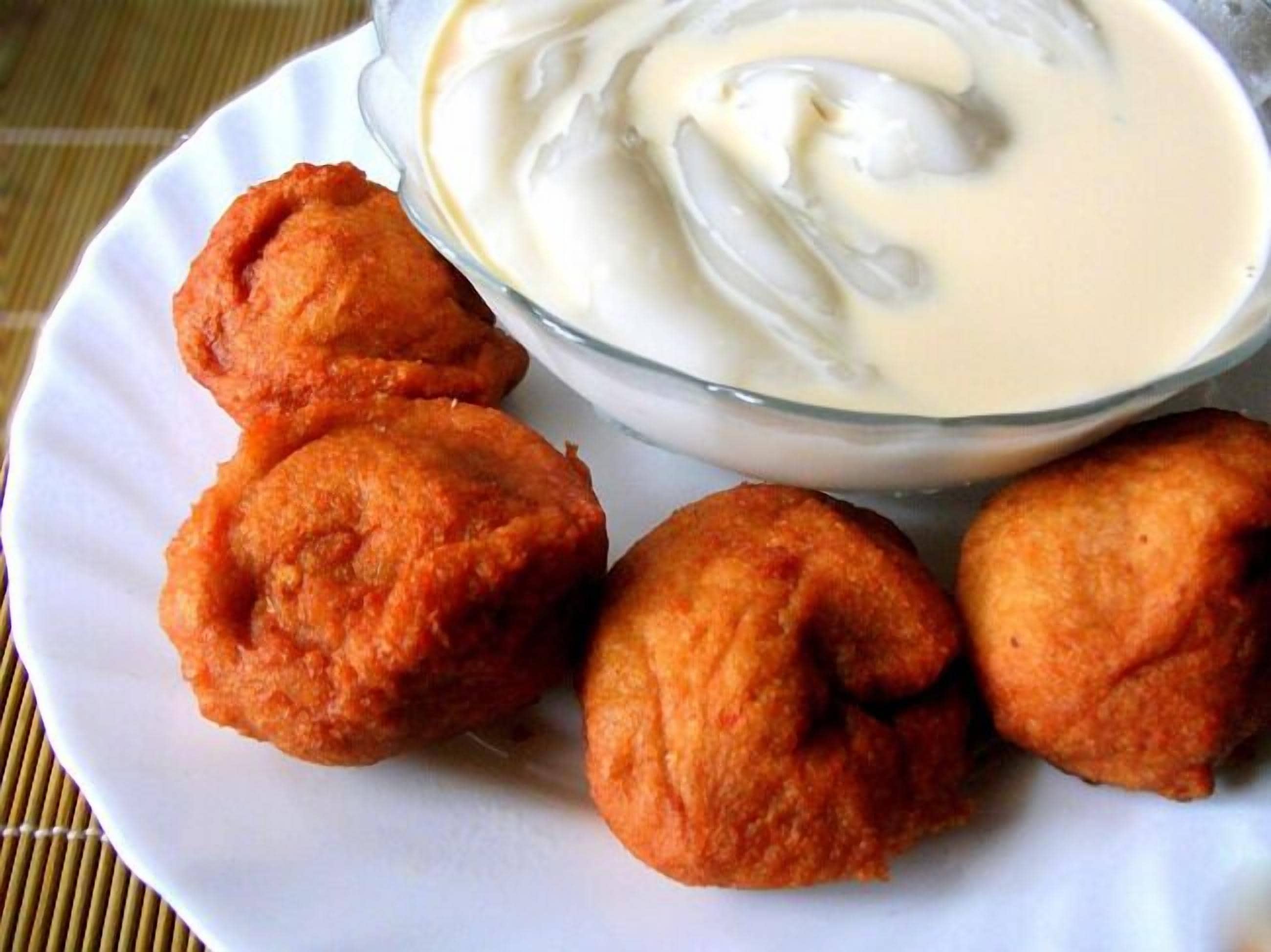 A plate with three fried items and a bowl of white sauce.