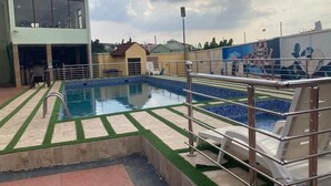 A swimming pool with a metal safety railing, surrounded by a tiled deck with green artificial grass accents. - Marchforte-Courtyard Hotel  (Ibadan)