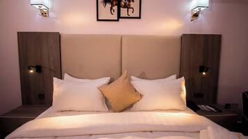 Una habitación de hotel con una cama grande, dos lámparas de pared y dos cuadros con caballos.