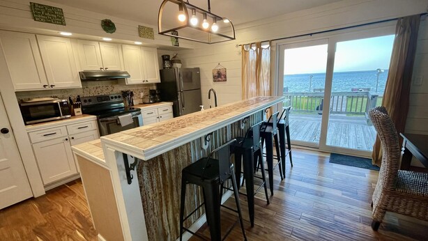 Eine Küche mit Bar, Holzboden und Meerblick.