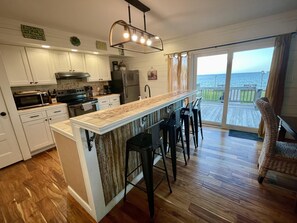 Eine Küche mit Bar, Holzboden und Meerblick.