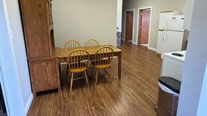 A dining area with a wooden table and chairs, a cabinet, and a refrigerator.