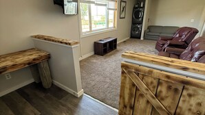 A spacious living area with a large window, a ceiling fan, a built-in speaker system, and a cozy seating area.