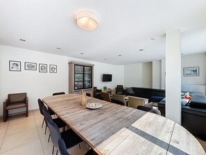 Un espacio habitable moderno con comedor, sofá, televisor y ventana.