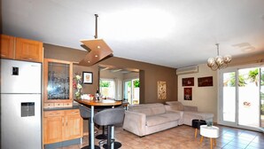 A modern kitchen with a dining area, a sofa, and a bar stool. - Awesome home in Saleilles (Saleilles)