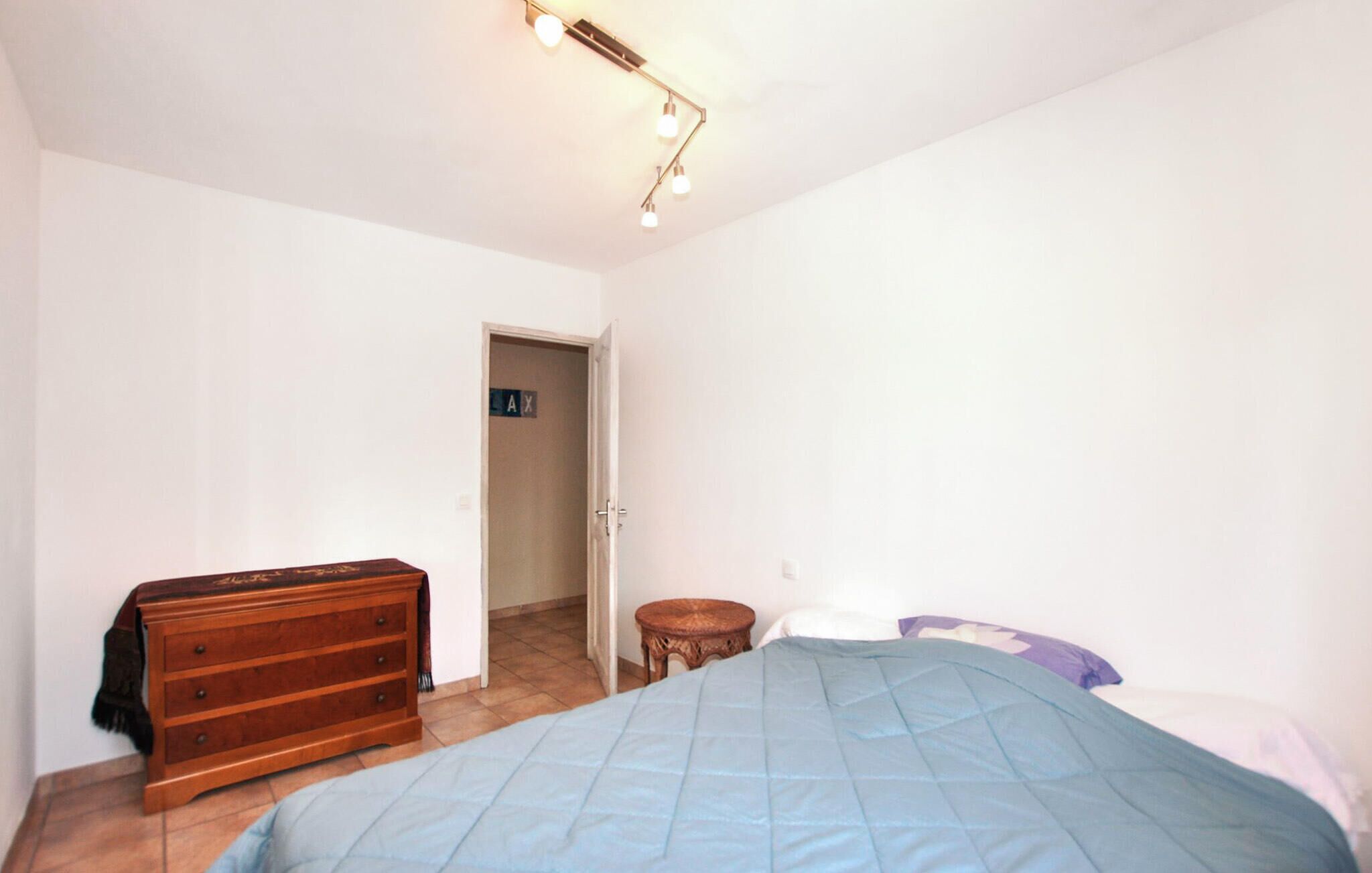 Ein Schlafzimmer mit einem Bett, einer Holzkommode, einem kleinen runden Tisch und einer Tür mit einem Schild.