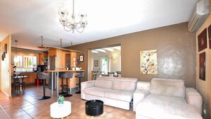 A modern living room with a sofa, a coffee table, and a dining area with a bar. - Awesome home in Saleilles (Saleilles)