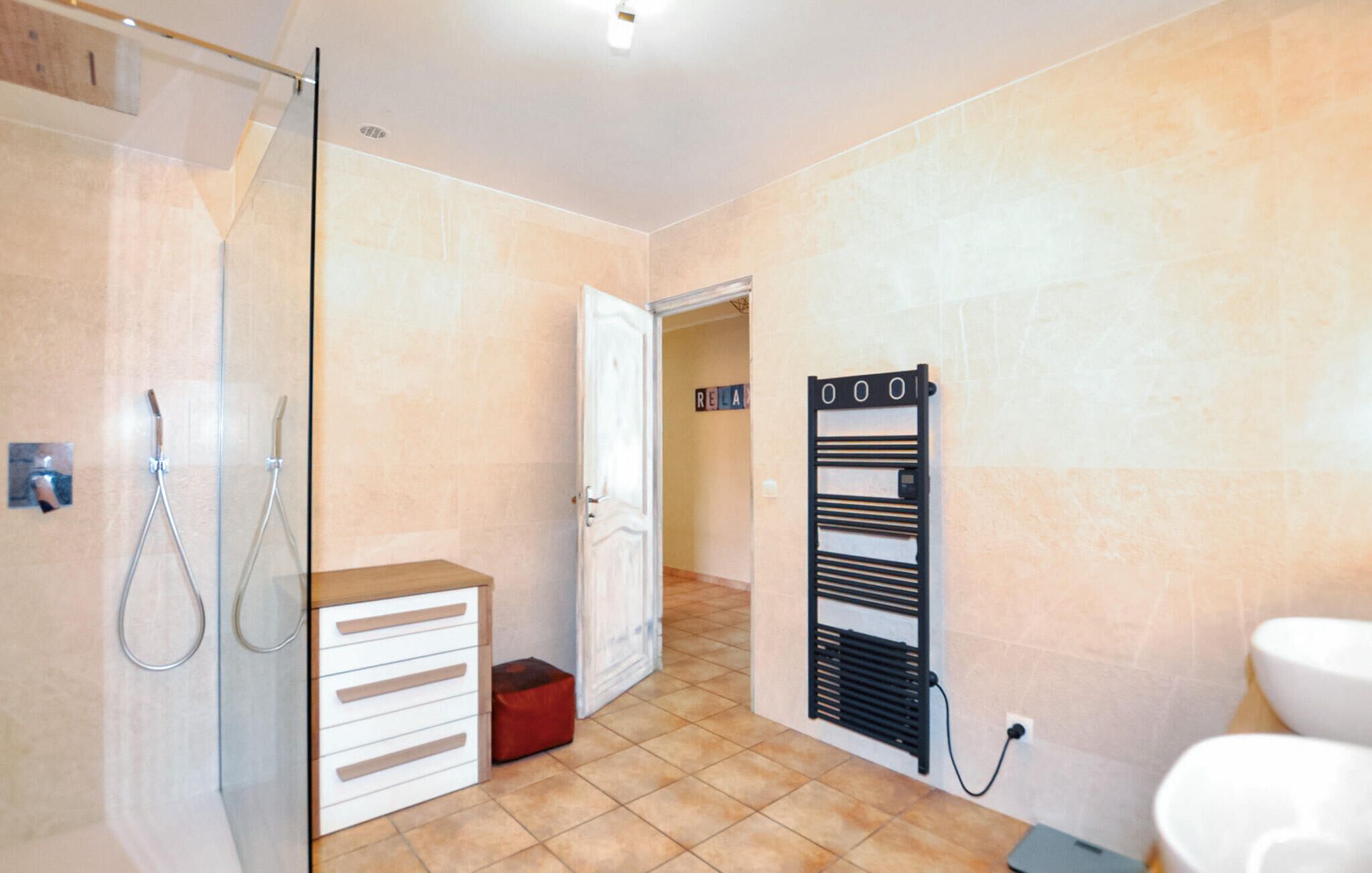 Une salle de bain équipée d’une douche, d’un porte-serviettes, de toilettes et d’un petit meuble de rangement.