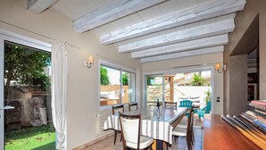 A dining area with a long table, chairs, and a view of the garden through large windows. - Awesome home in Saleilles (Saleilles)