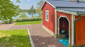 A red building with a stone foundation, a blue door, and a view of a lake. - 1 bedroom beautiful home in Tranås (Tranås)