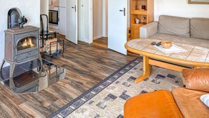 A cozy living room with a wood-burning stove, a sofa, a coffee table, and a bookshelf. - 1 bedroom beautiful home in Tranås (Tranås)