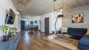 A modern living room with a dark blue sofa, a coffee table, and a TV mounted on the wall. - Beautiful home in Porec (Porec)