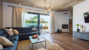 A modern living room with a dark blue sofa, a coffee table, and a fireplace. - Beautiful home in Porec (Porec)
