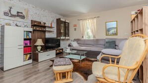 A living room with a sofa, a television, a wooden cabinet, and a bookshelf.