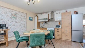 A compact kitchen with a dining area, featuring a brick wall, a wooden cabinet, a microwave, and a refrigerator.