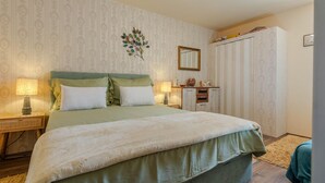 A neatly arranged bedroom with a large bed, two bedside tables with lamps, a dresser, and a wardrobe.