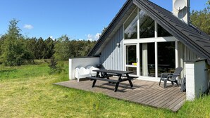 A modern house with a large glass door, a deck, and a chimney. - 2 bedroom cozy home in Fur (Fur)