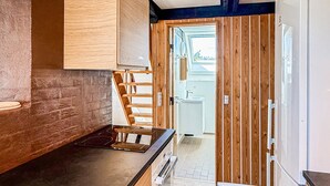 A kitchen with a wooden countertop, a built-in stove, and a view into a bathroom through a wooden door. - 2 bedroom cozy home in Fur (Fur)