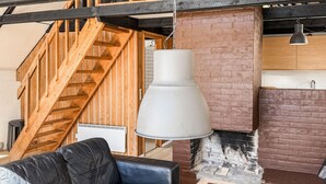 A modern interior with a wooden staircase, a hanging pendant light, a fireplace, and a leather sofa. - 2 bedroom cozy home in Fur (Fur)