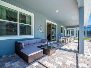 Relax in this stylish outdoor seating area with a sofa, chairs, and dining table.