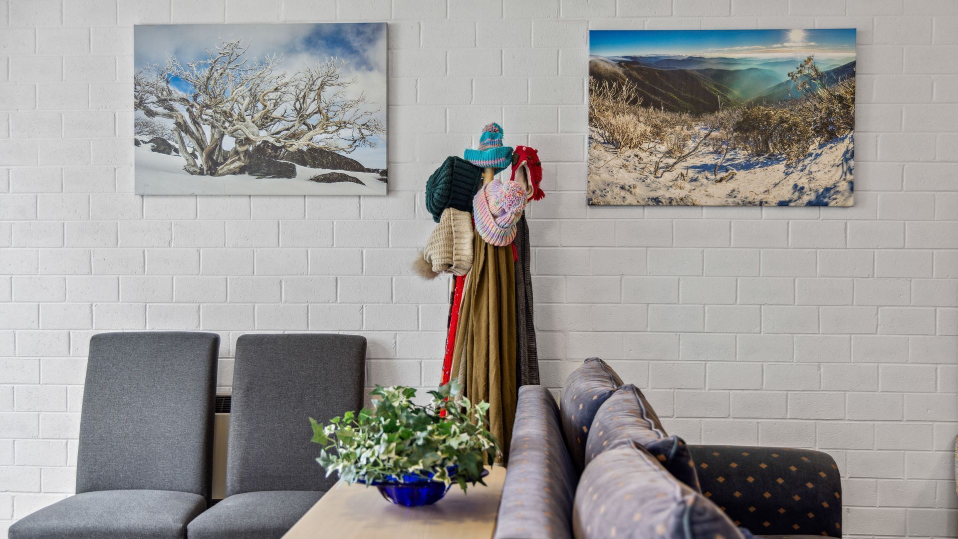 A living room with a sofa, two armchairs, a coffee table with a plant, and two paintings on the wall.