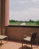 A balcony with a view of a rural landscape, a table, and a chair.